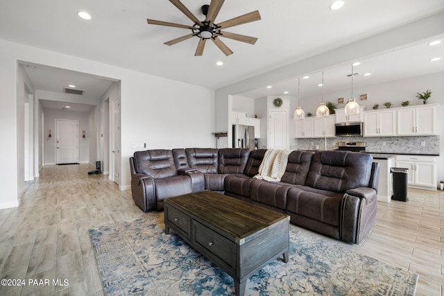 living room with ceiling fan and light hardwood / wood-style flooring