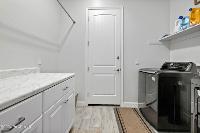 laundry room with cabinets, light wood-type flooring, and washer and dryer