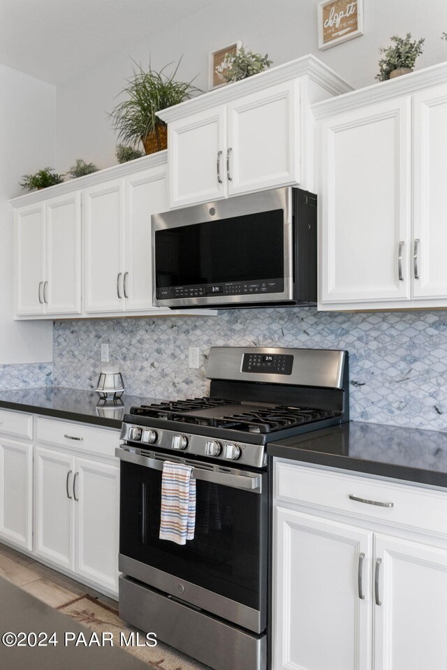 kitchen with white cabinets, appliances with stainless steel finishes, and backsplash