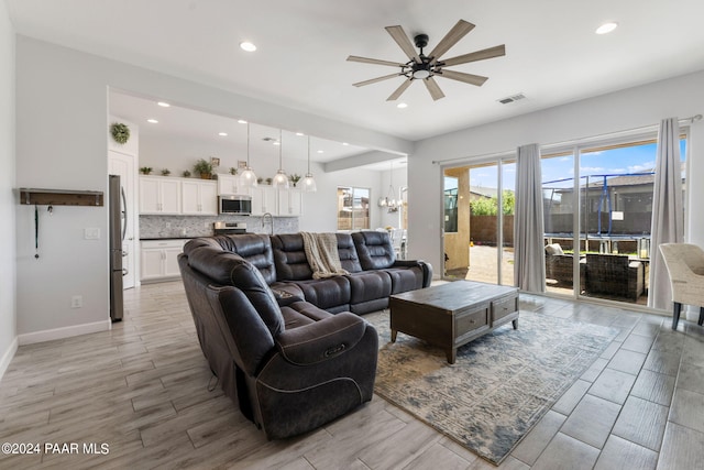 living room with ceiling fan with notable chandelier