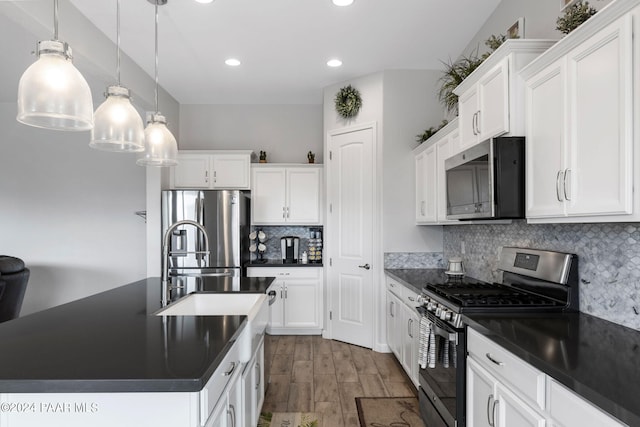 kitchen featuring white cabinets, stainless steel appliances, hanging light fixtures, and hardwood / wood-style floors