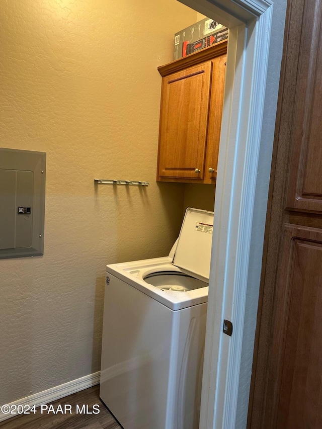 clothes washing area with washer / clothes dryer, electric panel, cabinets, and dark wood-type flooring