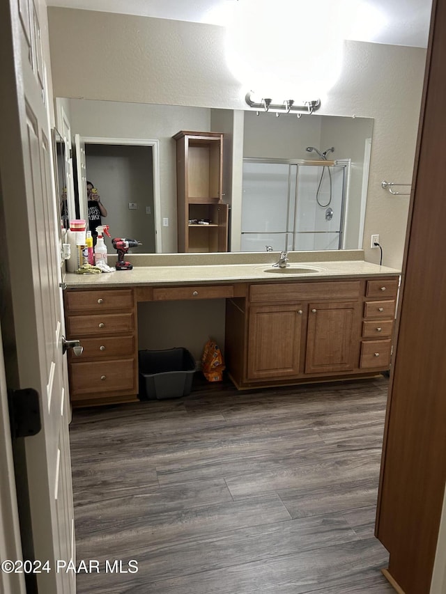 bathroom with hardwood / wood-style flooring, vanity, and a shower with door