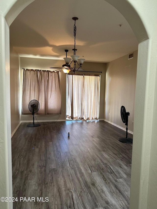 spare room with dark hardwood / wood-style floors and an inviting chandelier