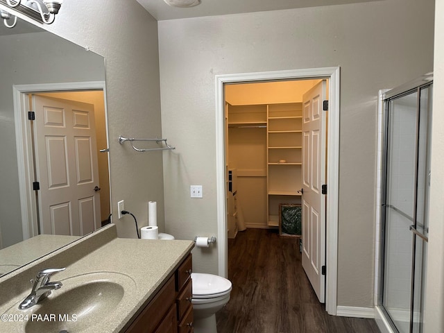 bathroom featuring hardwood / wood-style floors, vanity, toilet, and a shower with shower door