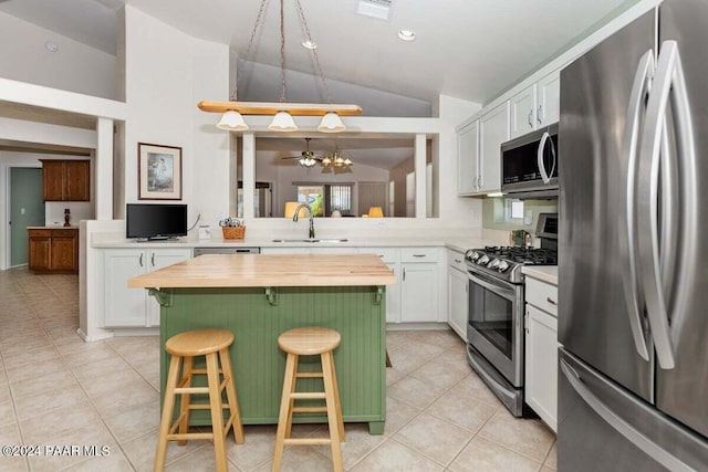 kitchen with a breakfast bar, white cabinets, vaulted ceiling, appliances with stainless steel finishes, and a kitchen island