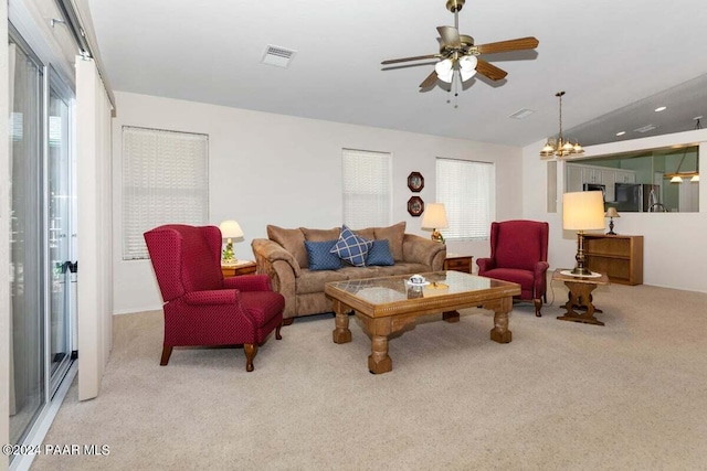 carpeted living room with ceiling fan with notable chandelier and lofted ceiling