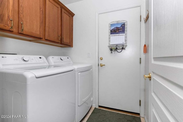 clothes washing area with cabinets and washer and clothes dryer