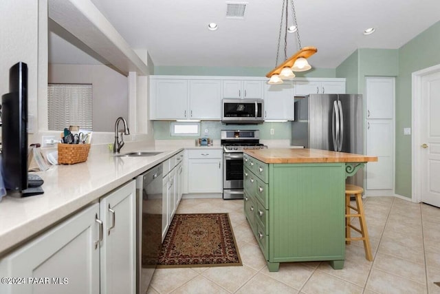 kitchen with white cabinets, appliances with stainless steel finishes, green cabinets, and a breakfast bar area