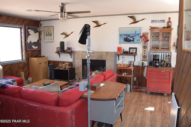 25633 W El Dorado Dr, Seligman, AZ 86337 - living room with wooden walls, visible vents, ceiling fan, a tiled fireplace, and wood finished floors