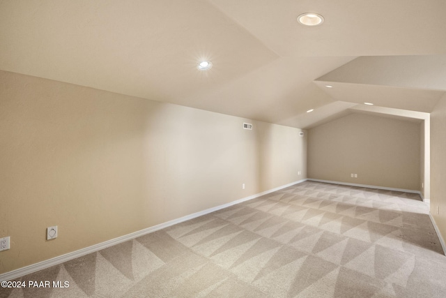 additional living space with light carpet and vaulted ceiling