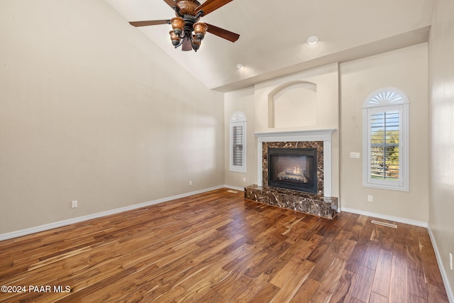 unfurnished living room featuring hardwood / wood-style floors, ceiling fan, a high end fireplace, and high vaulted ceiling