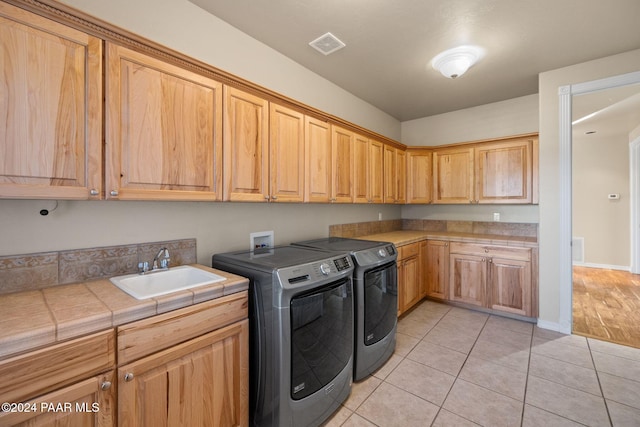 laundry area with cabinets, independent washer and dryer, sink, and light tile patterned floors