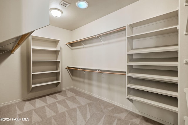 walk in closet featuring light colored carpet