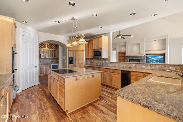 kitchen featuring sink, stainless steel microwave, a center island, tasteful backsplash, and hardwood / wood-style flooring