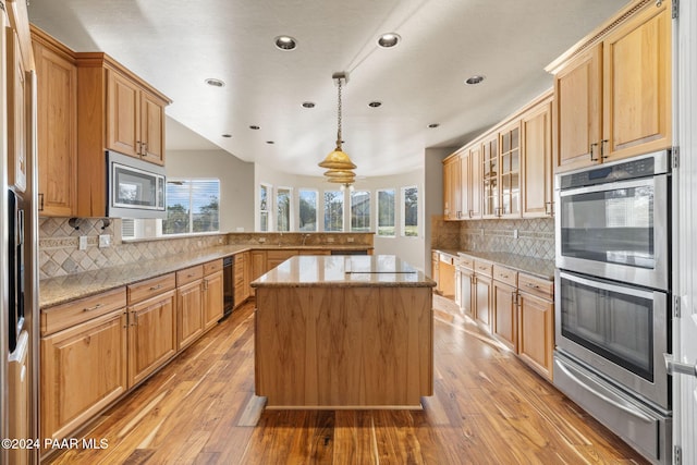 kitchen featuring decorative light fixtures, a center island, light wood-type flooring, and stainless steel appliances