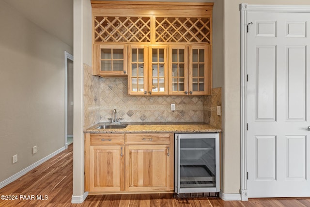 bar with light stone countertops, sink, dark wood-type flooring, beverage cooler, and decorative backsplash