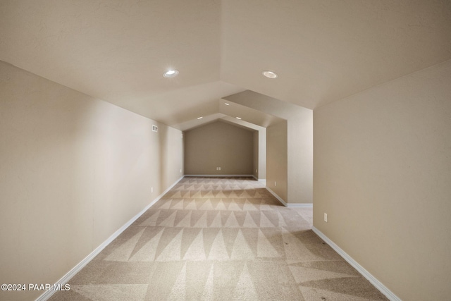 additional living space featuring light colored carpet and lofted ceiling