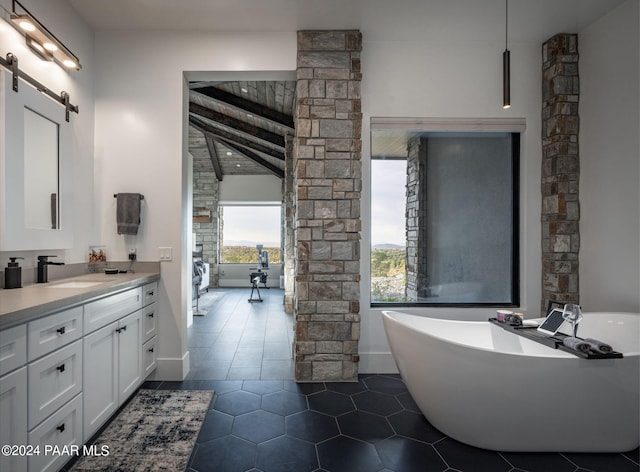 bathroom with vaulted ceiling with beams, tile patterned flooring, vanity, and a bath