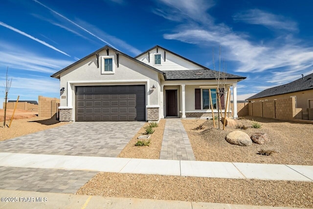 view of front facade featuring fence, a shingled roof, stucco siding, a garage, and decorative driveway