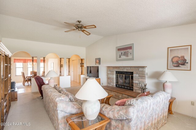 carpeted living room featuring a fireplace, a textured ceiling, ceiling fan, and lofted ceiling