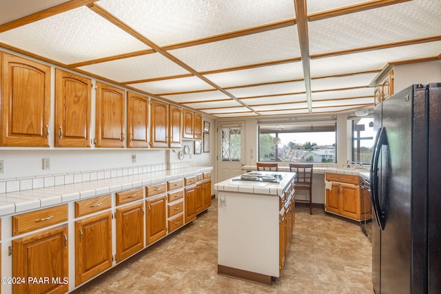 kitchen with a textured ceiling, tile counters, a kitchen island, and stainless steel appliances