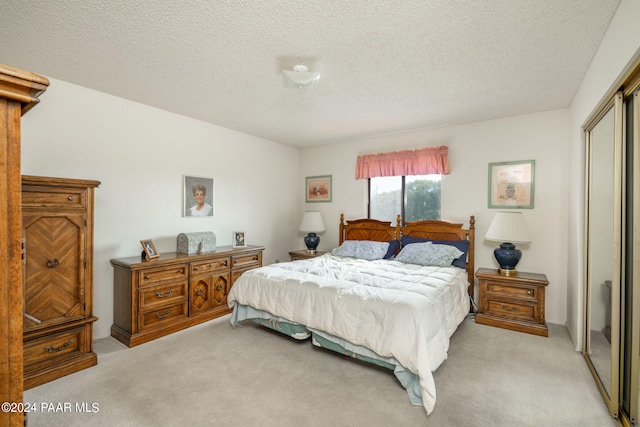 bedroom featuring a closet, light colored carpet, and a textured ceiling