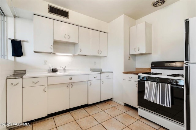 kitchen featuring white cabinetry, sink, light tile patterned floors, and white appliances