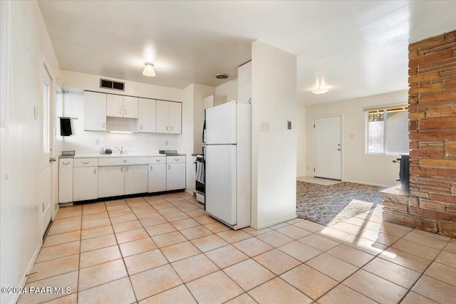 kitchen with white cabinets, white fridge, stainless steel range, and light tile patterned flooring