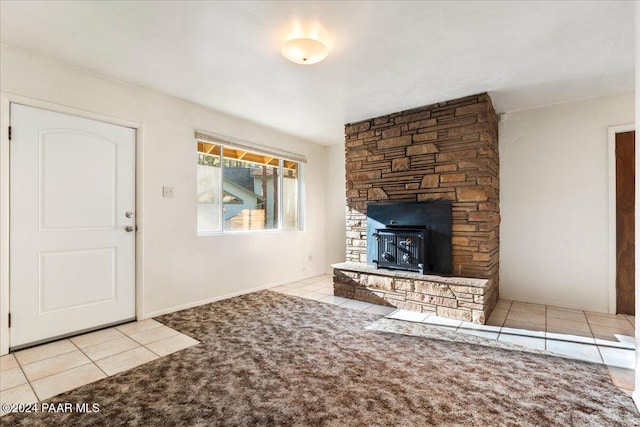 unfurnished living room with a wood stove and light tile patterned floors