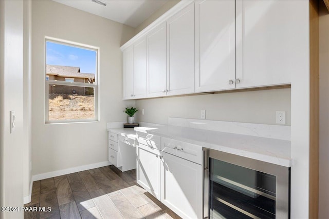 kitchen with wine cooler, white cabinetry, light stone countertops, and light wood-type flooring