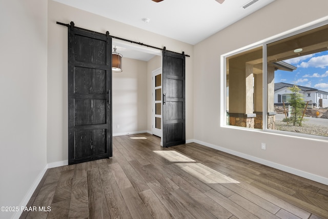 unfurnished room with a barn door and hardwood / wood-style floors