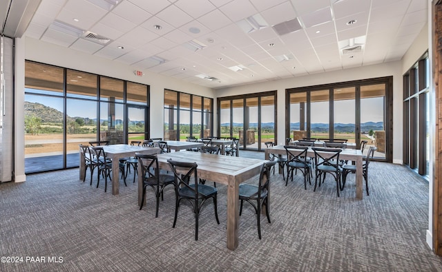 carpeted dining room with a drop ceiling and a mountain view