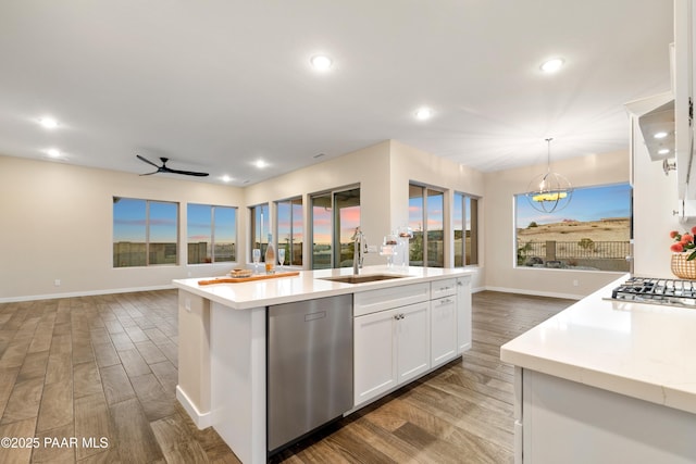 kitchen featuring sink, appliances with stainless steel finishes, white cabinetry, a center island with sink, and decorative light fixtures