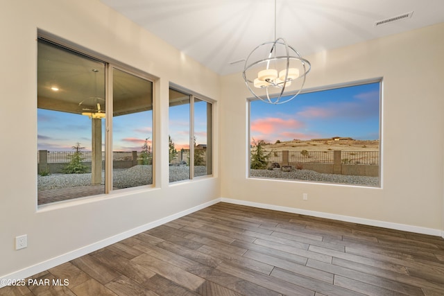 unfurnished dining area with an inviting chandelier, hardwood / wood-style floors, and a wealth of natural light