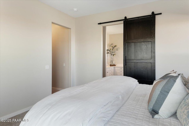 carpeted bedroom with a barn door and connected bathroom