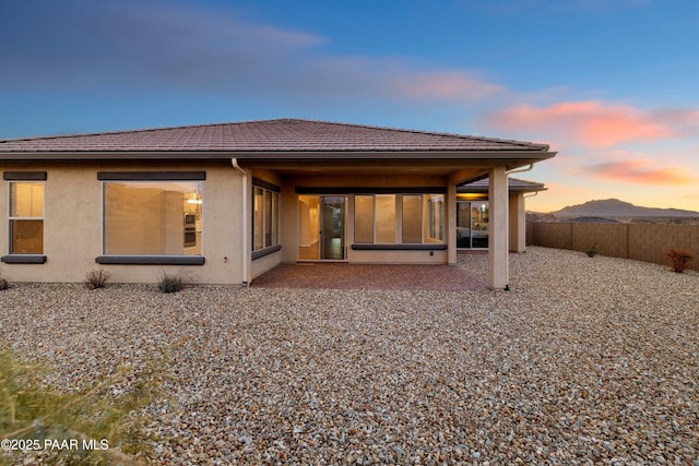 back house at dusk featuring a mountain view and a patio area