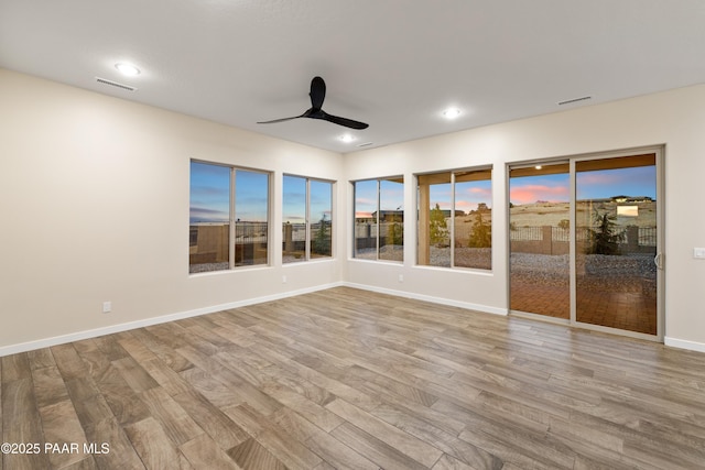 empty room with ceiling fan and light hardwood / wood-style flooring