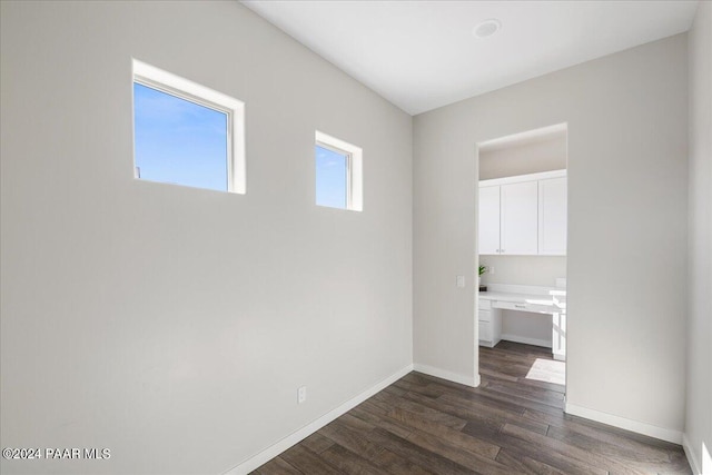 spare room with dark hardwood / wood-style floors and built in desk