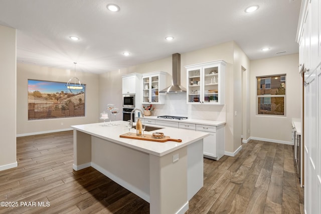 kitchen with white cabinetry, appliances with stainless steel finishes, sink, and wall chimney range hood