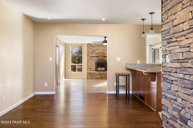 interior space with dark hardwood / wood-style floors, kitchen peninsula, pendant lighting, a kitchen bar, and a fireplace