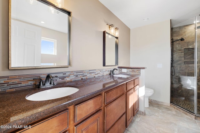 bathroom with vanity, toilet, a shower with shower door, and tasteful backsplash