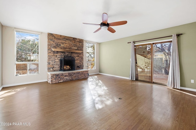 unfurnished living room featuring a fireplace, hardwood / wood-style flooring, ceiling fan, and a healthy amount of sunlight