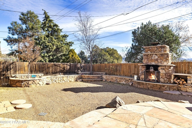 view of yard featuring an outdoor stone fireplace and a patio