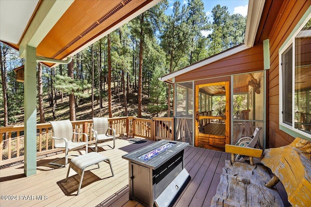 deck featuring an outdoor fire pit and a sunroom