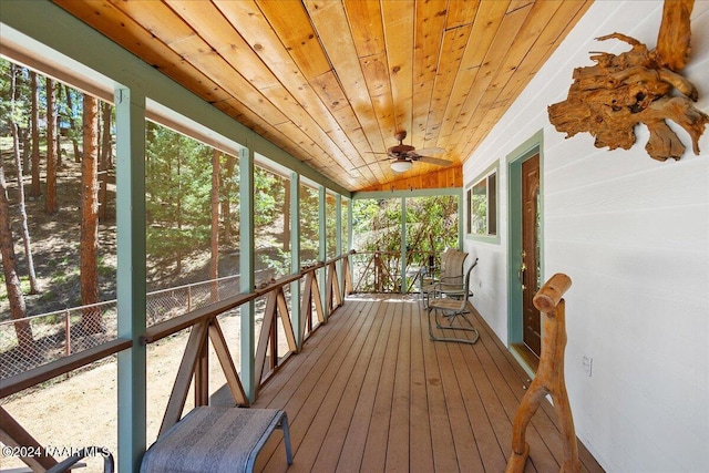 unfurnished sunroom with a ceiling fan, vaulted ceiling, wood ceiling, and a wealth of natural light