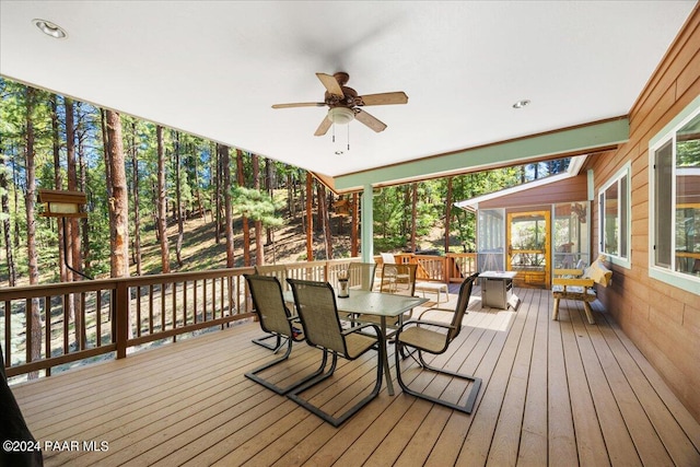 deck with outdoor dining space, a sunroom, and ceiling fan