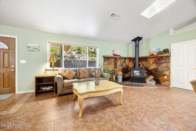 living room with lofted ceiling with skylight, a wood stove, baseboards, and visible vents