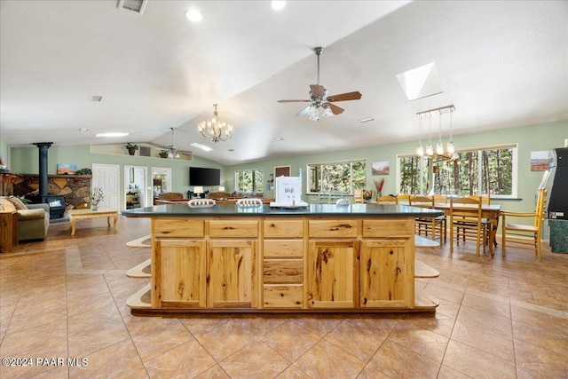 kitchen featuring dark countertops, a wood stove, open floor plan, and vaulted ceiling