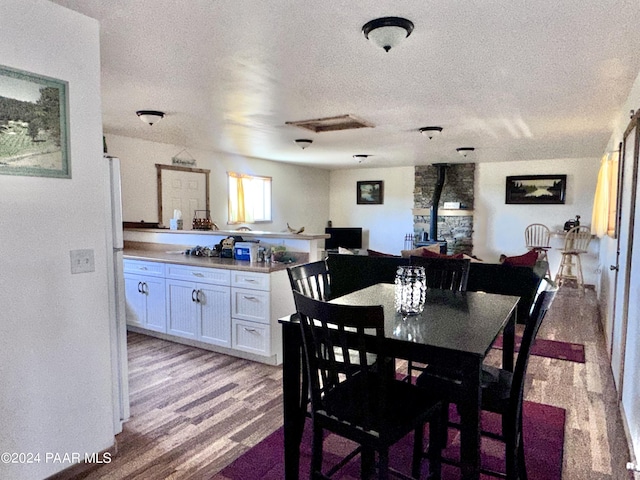 dining room with a wood stove, light hardwood / wood-style floors, and a textured ceiling